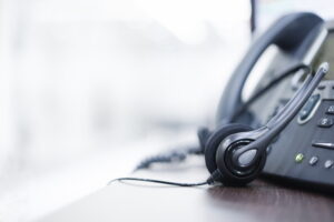 close up on headset devices of call center career with telephone voip on table of helpdesk agency t20 NGr672